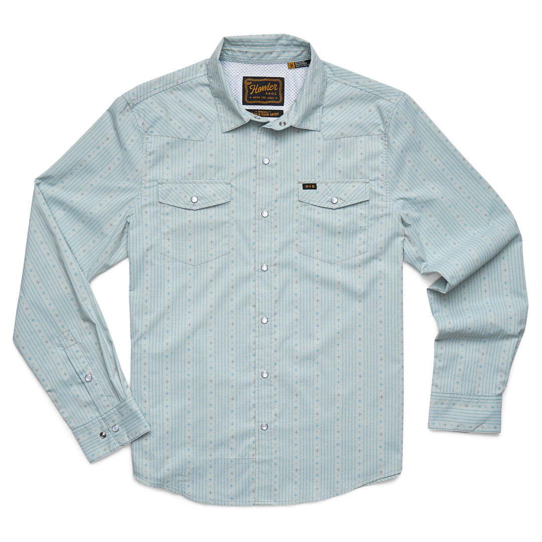 The Howler Brothers H Bar B Tech Long Sleeve shirt in light blue, shown laid flat on a white background, features subtle vertical stripes, two chest pockets, stretch nylon-poly fabric for comfort, and UPF 35 sun protection.