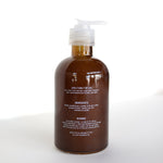 A brown pump bottle of Ballad of the Bird Dog Hand Soap with white text showing directions, Santal essential oil ingredients, and warnings stands on a white surface against a bright background.