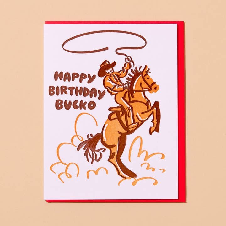The "Happy Birthday Bucko" card by And Here We Are features a cowboy on a rearing horse and brown "Happy Birthday Bucko" text.