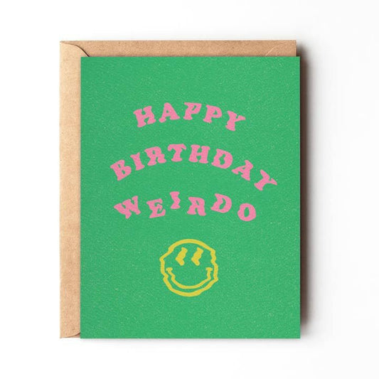 The "Happy Birthday Weirdo" card by Daydream Prints features bold pink text above a yellow smiley face on green cardstock and comes with a brown envelope. Designed in Portland, Oregon.