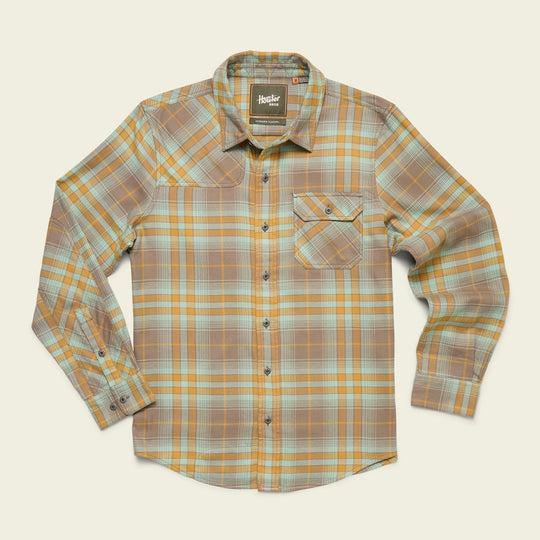 The Howler Brothers Harker's Flannel is a long-sleeve, button-up shirt in tan, light blue, and orange shades, made from buttery soft flannel with a single front chest pocket featuring a buttoned flap.