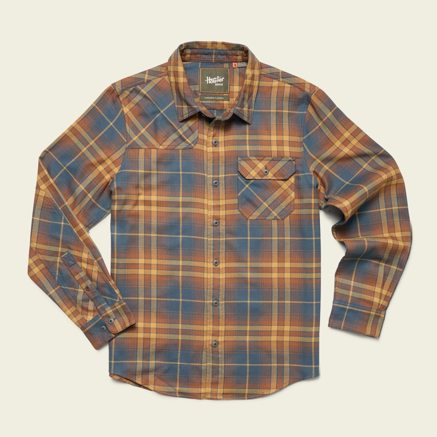 The Harker's Flannel by Howler Brothers is a buttery soft men's long-sleeve button-up, featuring blue, yellow, and orange plaid with a single chest pocket, shown laid flat on a light background.