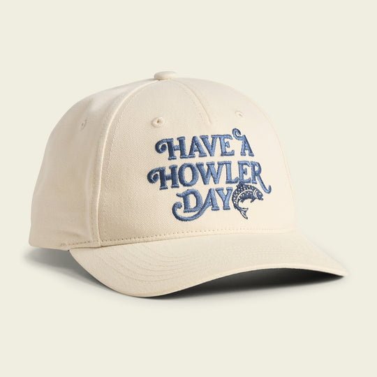 The Have a Howler Day cap by Howler Brothers features beige fabric, blue "HAVE A HOWLER DAY" embroidery above a jumping fish, classic Howler artwork, and a comfy snapback closure for a perfect fit.
