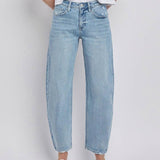 A person wearing Vervet High Rise Light Wash Barrel Leg Jeans with a white t-shirt and white flat shoes stands against a plain background.