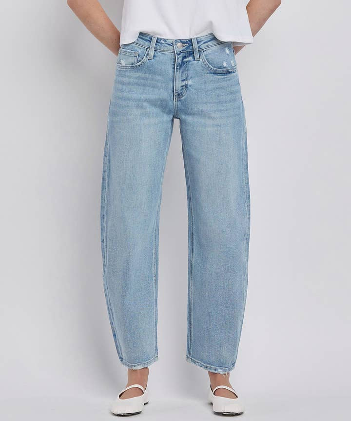 Person wearing Vervet High Rise Light Wash Barrel Leg Jeans, a white t-shirt, and white flats, standing against a plain light background.