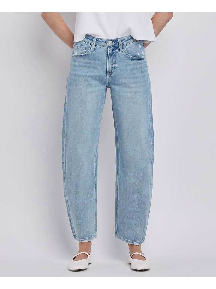 A person wearing Vervet High Rise Light Wash Barrel Leg Jeans with a white t-shirt and white flat shoes stands against a plain background.