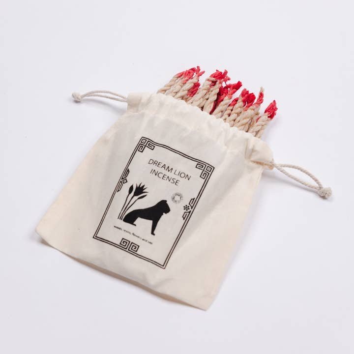 The "Himalayan Sweet Ropes | Dream Lion" drawstring bag by Dream Lion Incense features a lion graphic and holds hand-rolled Nepalese incense ropes with red tips, crafted from aromatic Himalayan herbs.