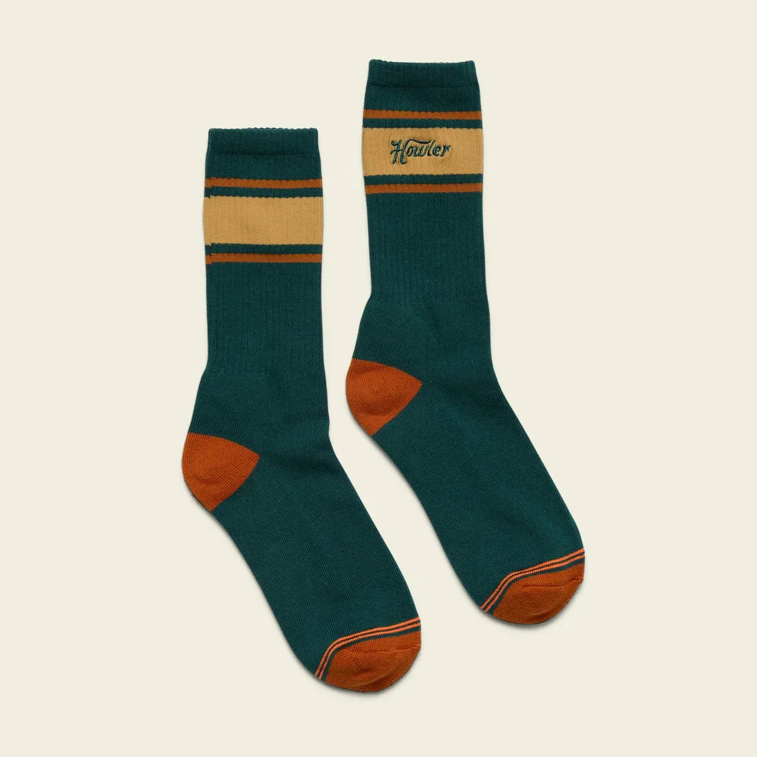 The Howler Brothers Howler Script Socks are vintage-inspired green athletic crew socks with orange toes and heels, gold and orange stripes at the top, and "Howler" embroidered in gold.