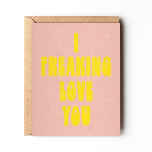 The "I Freaking Love You" greeting card by Daydream Prints features bold yellow text on a pink retro design and comes with a brown envelope.
