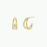 The Illusion Double Hoop by JaxKelly features 18k gold-plated, tarnish-free hoops with a modern, twisted design. Shown from front and side on a plain white background.
