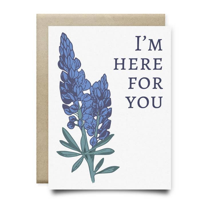 The "I'm Here Bluebonnets Sympathy Card" by Anvil Cards features two hand-drawn bluebonnets and the message "I'M HERE FOR YOU" on sustainable linen paper, displayed atop a brown envelope.