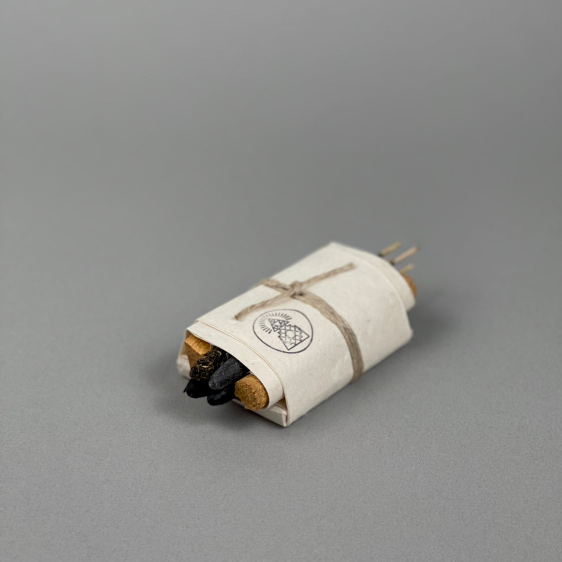 The Bath & Meditate Bundle by Incausa features incense sticks and charcoal, wrapped in white Nepalese Lokta paper and tied with string, displayed on a plain gray background.