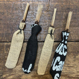 Four bundles of Ballad of the Bird Dog Incense Sticks | Tattoo Ink, wrapped in burlap and upcycled coffee bags, are arranged side by side on a wooden surface.