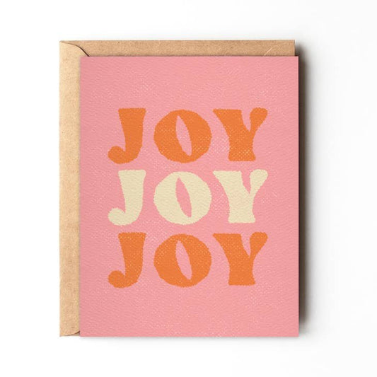 The Joy Joy Joy holiday card by Daydream Prints features "JOY" three times in bold, textured orange and cream seventies font for a retro California beach vibe.