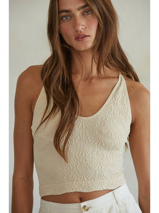 Woman with long brown hair wears the By Together Knit Modal Nylon Spandex Seamless Jacquard Tank with high-waisted white pants, standing against a neutral background.