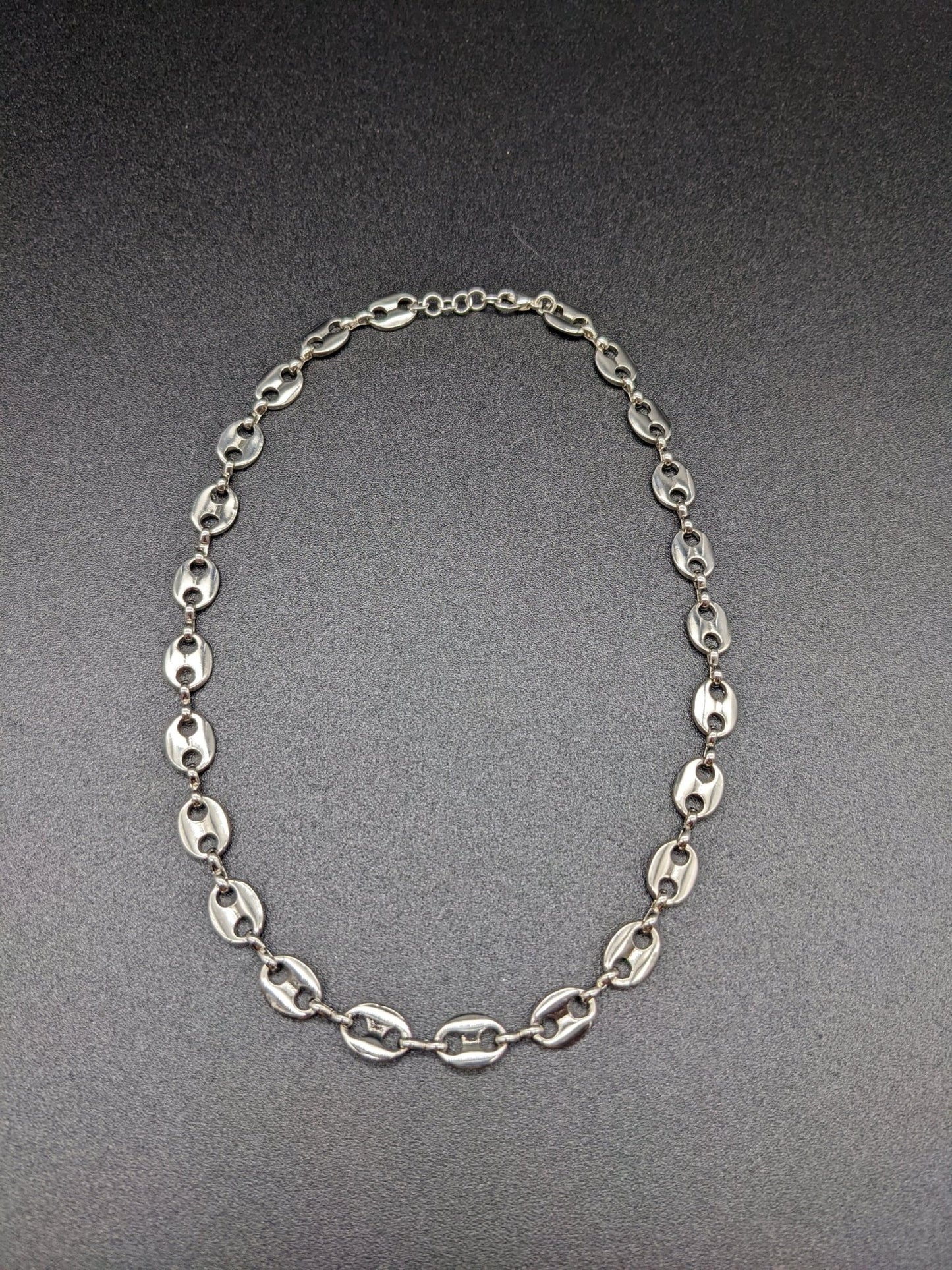 The Koffee Necklace by Minh Atelier, featuring silver plated oval links, is displayed on a plain black background—ideal for fans of classic choker necklace styles.