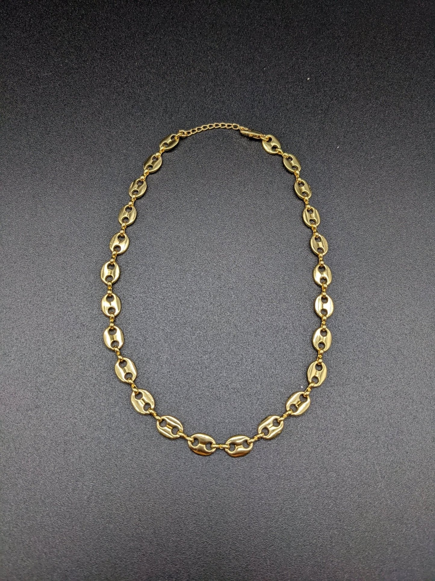 The Koffee Necklace by Minh Atelier, a gold plated choker with oval links, is shown against a plain black background.
