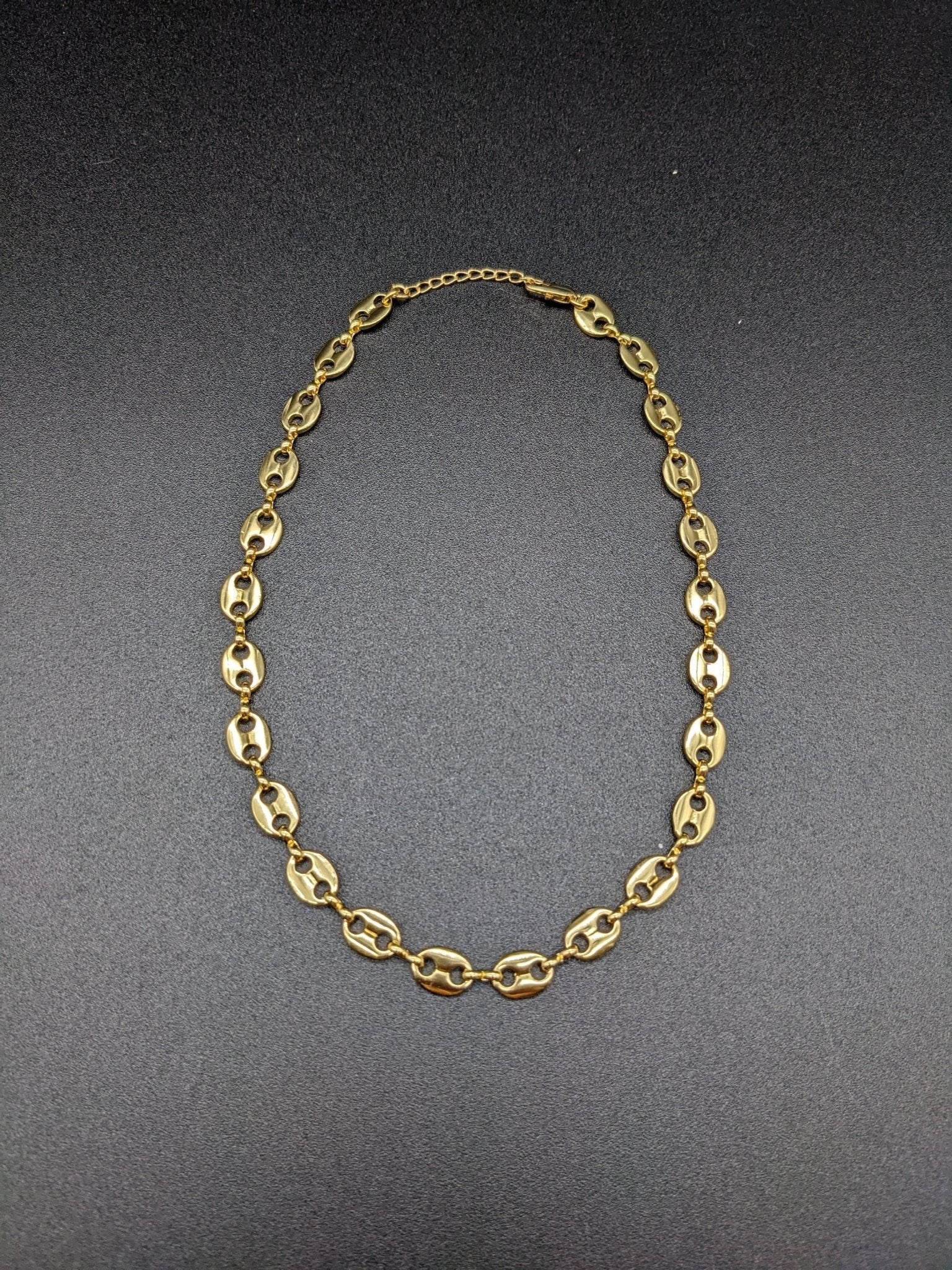 The Koffee Necklace by Minh Atelier, a gold plated choker with oval links, is shown against a plain black background.