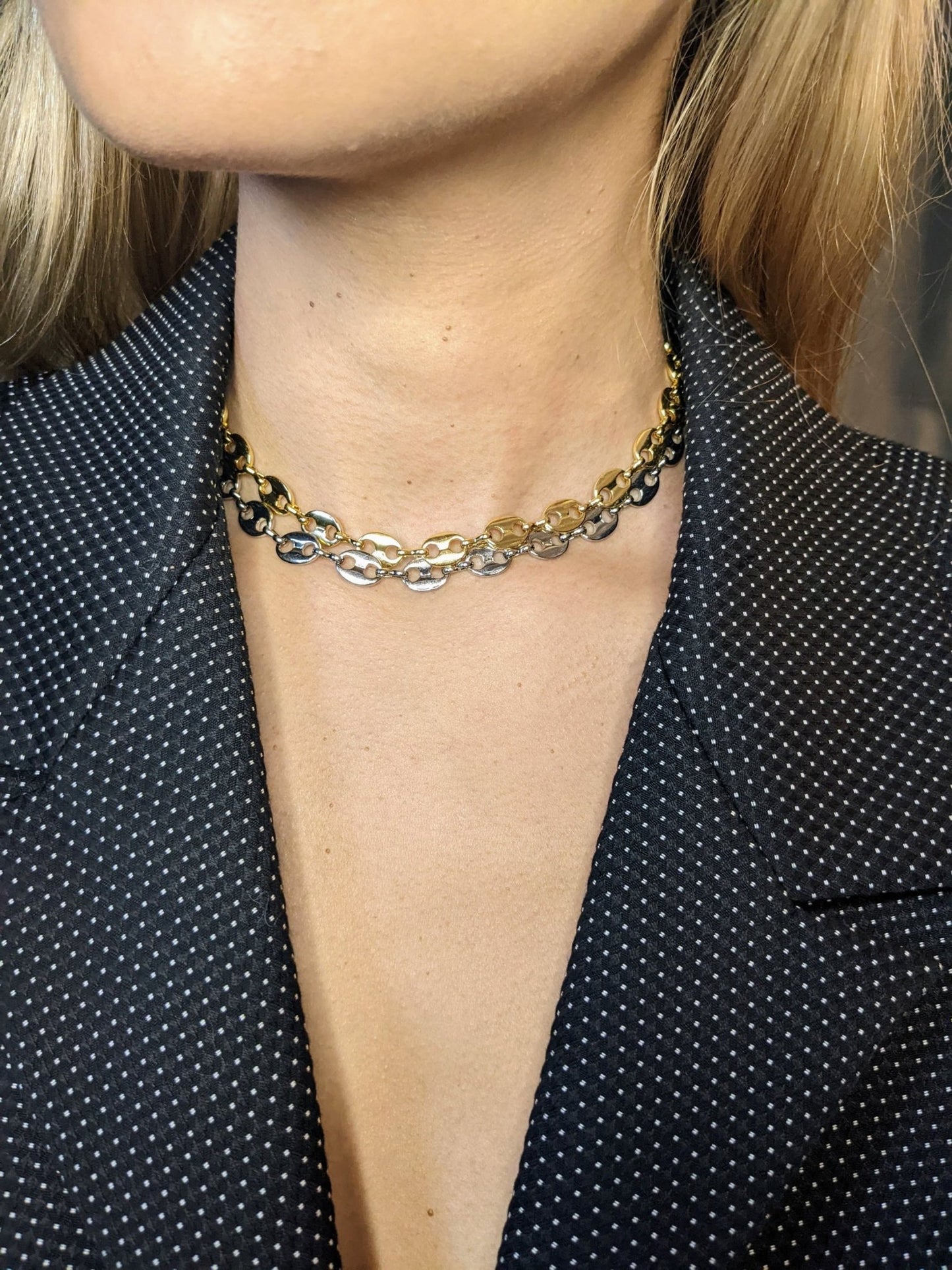 Close-up of a person wearing a black blazer with white polka dots, styled with the Koffee Necklace by Minh Atelier, a striking gold-plated choker.
