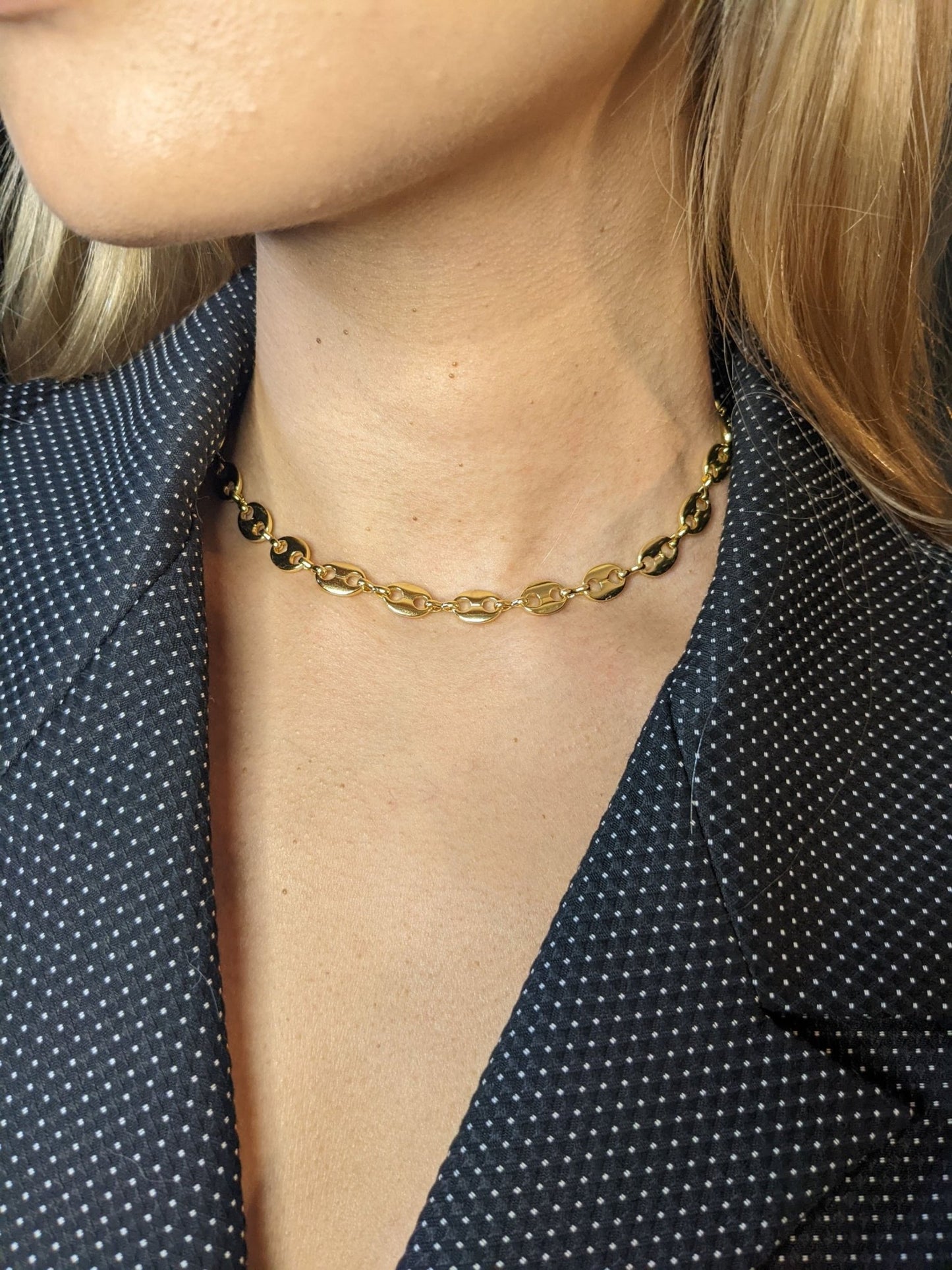 A woman wearing the Koffee Necklace by Minh Atelier and a dark blazer with white dots.