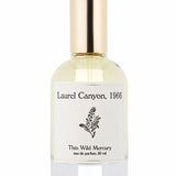 A clear glass bottle with a gold cap, labeled "Laurel Canyon | Thin Wild Mercury" by Thin Wild Mercury, features a black botanical illustration, evoking patchouli notes and the woody essence of canyon air.