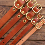 Five brown leather dog collars by Ballad of the Bird Dog, featuring brass buckles and D-rings, are displayed side by side on wood, each highlighting the craftsmanship of a Leather Dog Collar from Ballad of the Bird Dog.