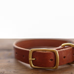 The Leather Dog Collar by Ballad of the Bird Dog, made from English bridle leather with a brass buckle, is shown resting on a wooden surface.