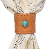 The Jenni Earle Leather Studded Bandana Slide features brown genuine oiled leather with a turquoise stone accent and holds a cream napkin with black stitched lines.