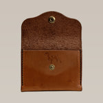 The Handcrafted Leather Wallet - Small Card Holder by Ballad of the Bird Dog features artisanal brown leather, a snap button closure, and an embossed dog figure on the front panel.