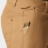 Close-up of Duck Camp Lightweight Brush Pants’ durable cotton blend pocket with a folding knife featuring an engraved handle partially tucked inside the small front pocket.