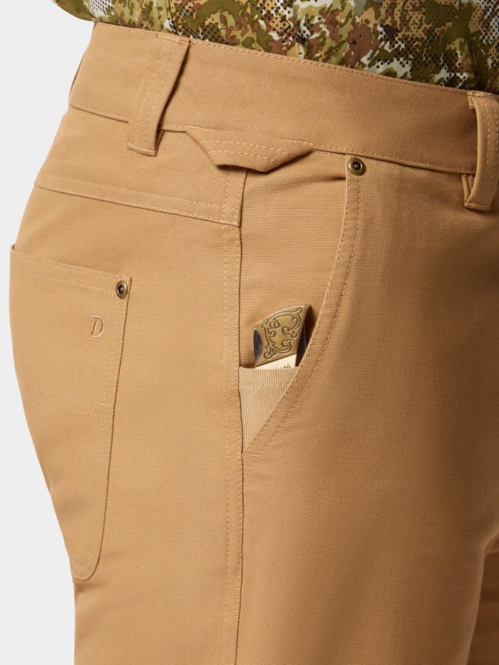 Close-up of Duck Camp Lightweight Brush Pants’ durable cotton blend pocket with a folding knife featuring an engraved handle partially tucked inside the small front pocket.
