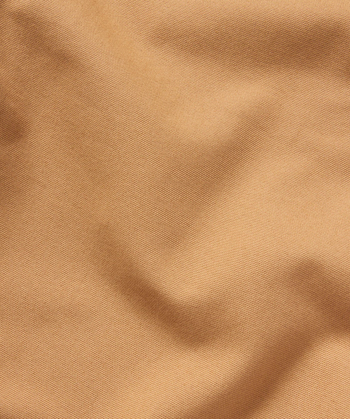 Close-up of light brown, textured fabric with gentle folds highlights the quality material of Duck Camp's Lightweight Brush Pants—a durable cotton blend designed for comfort and resilience.
