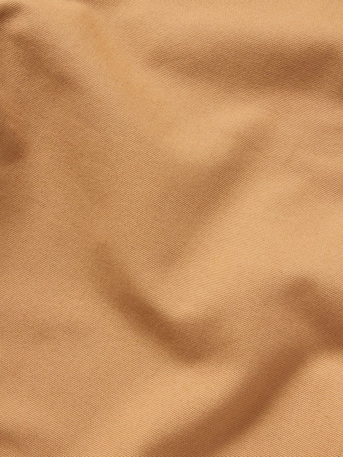 Close-up of Duck Camp Lightweight Brush Pants in light brown, featuring durable cotton blend fabric with visible texture and slight folds.