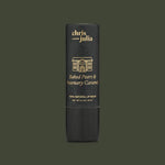 A black tube of Poppy & Pout Lip Balm in Baked Pears & Rosemary Caramel is shown against a dark green background. This cruelty-free lip balm is made with 100% natural ingredients.