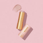 An open Poppy & Pout Lip Balm tube rests on a pink surface, with a swatch of balm above it.