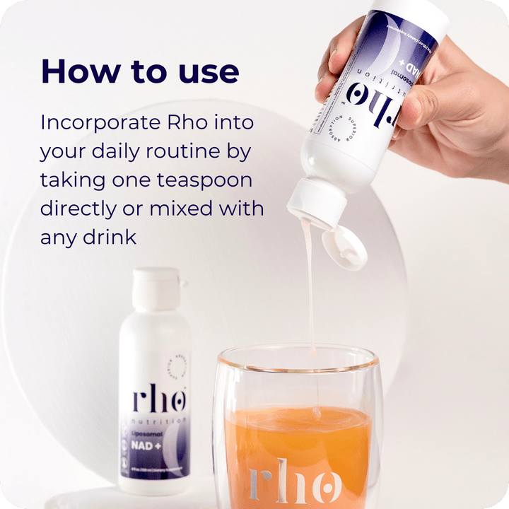 A hand pours Rho Nutrition’s Liposomal NAD+ supplement, designed to support cellular energy and healthy aging, from a bottle into an orange drink, with another Rho Nutrition bottle and daily NAD+ instructions in the background.