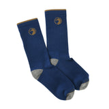 Duck Head’s Logo Sock is a blue crew sock with gray toes and heels, brown trim at the cuffs, and a brown circular logo near the top—a classic accessory for any outfit.