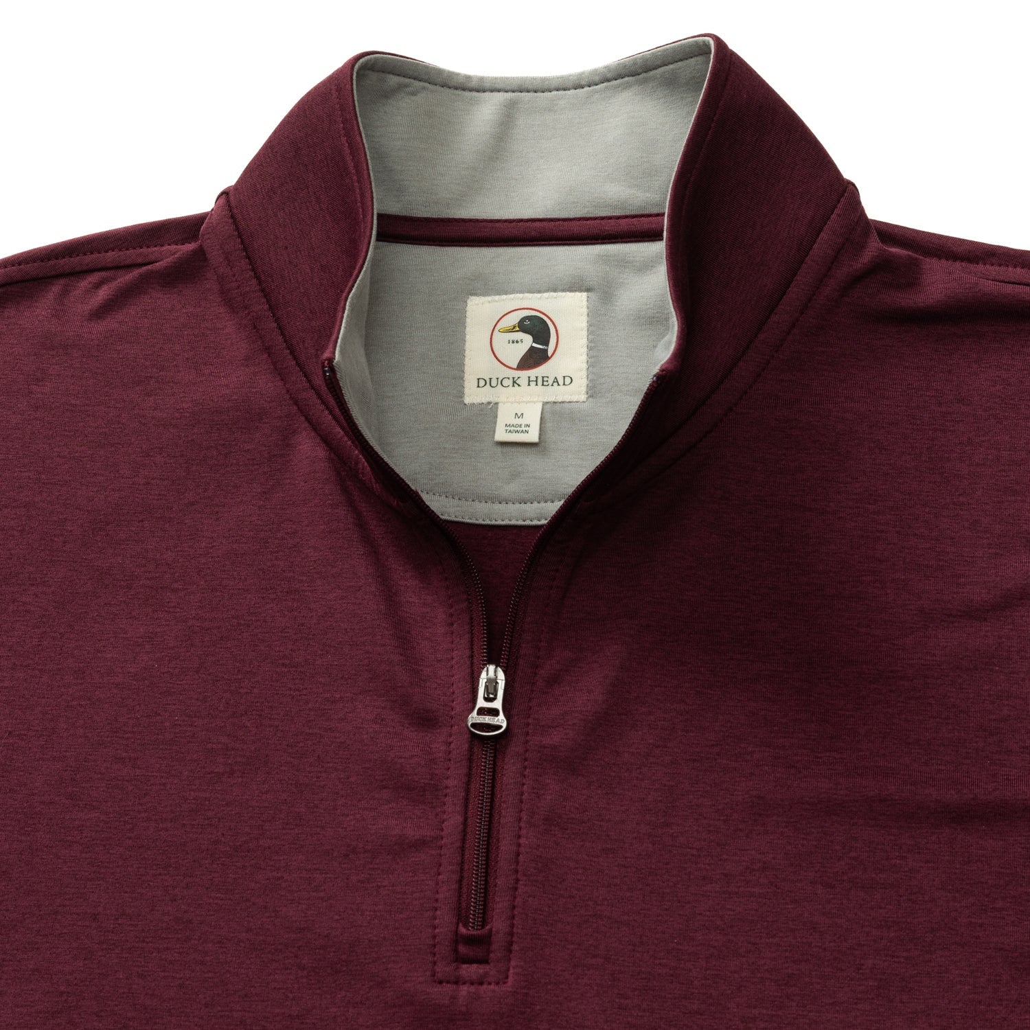 The Duck Head Long Drive Performance 1/4 Zip Pullover features a maroon color, stand collar, grey inner lining, visible neck brand tag, and moisture-wicking performance fabric for comfort and style.