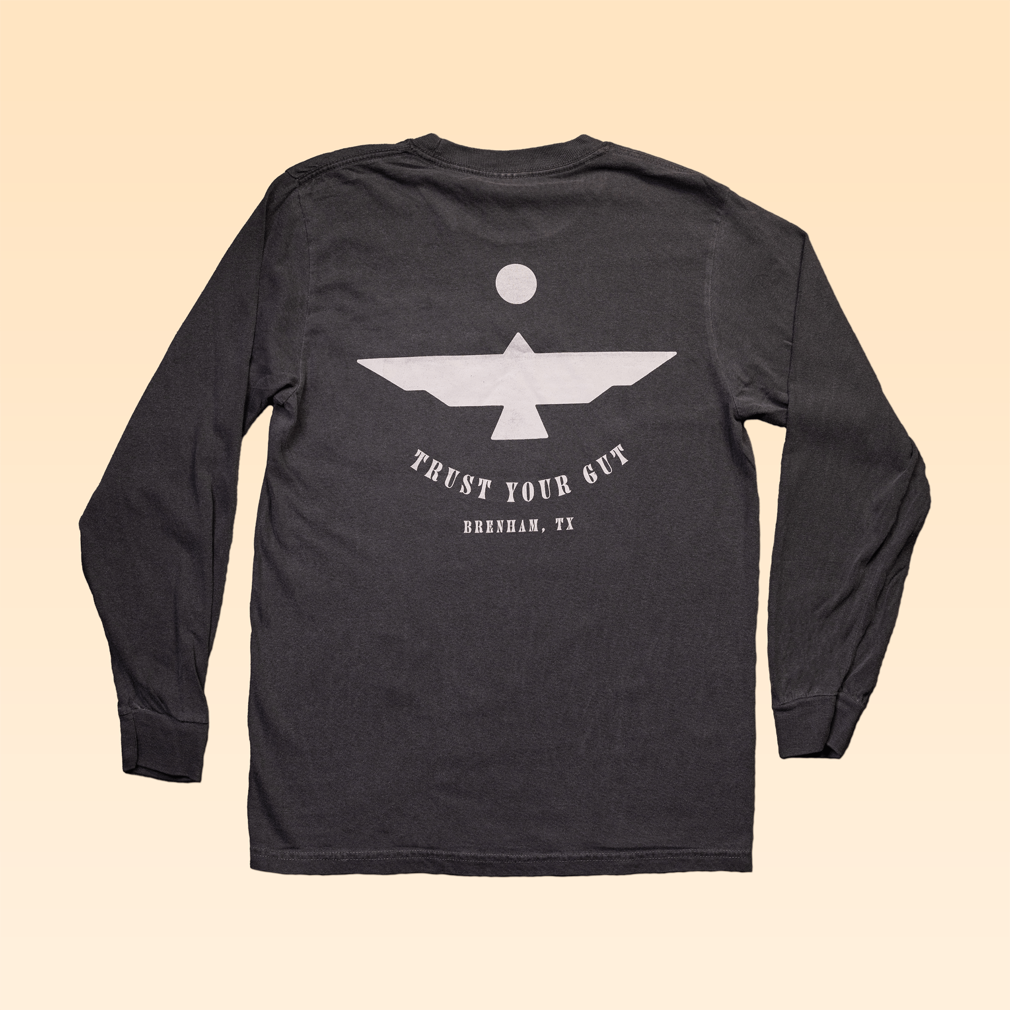 The Shop Shirt Long Sleeve | Thunderbird by Ballad of the Bird Dog features a white geometric bird and "Trust Your Gut, Brenham, TX" on the back—an adventure tee for bold style lovers.