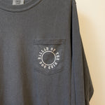 The Ballad of the Bird Dog Shop Shirt Long Sleeve | Thunderbird is a dark gray tee with a chest pocket featuring a circular "BALLAD OF THE BIRD DOG" design—ideal for adventure lovers and pocket tee fans.