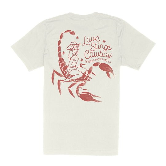 The LOVE STINGS T-SHIRT by Sendero Provisions Co. features a bold red graphic of a cowgirl on a scorpion and “Love Stings Cowboy Sendero Provisions Co” on the back—a tribute to tough cowgirls who demand respect.