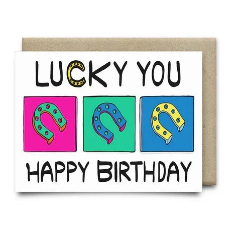 The Lucky You Happy Birthday Card by Anvil Cards features three colored squares with horseshoe illustrations, "Lucky You Happy Birthday" text, is A2 size, printed on linen paper, and blank inside for your own message.