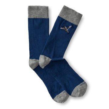 The Mallard Sock by Duck Head is a blue cotton blend pair with gray toes, heels, and cuffs, and features a small embroidered flying mallard on the side.