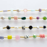 The Mariposa Bracelet by Jill Makes features four gold wires adorned with assorted gemstone beads in round, faceted, and irregular shapes in pastel, bright, and neutral hues, displayed on a white background.
