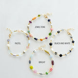 Four Mariposa Bracelets by Jill Makes—pastel, jewel tone, black & white, and bright—are arranged in a circle. Each features gemstone beads and an adjustable chain for the perfect fit.