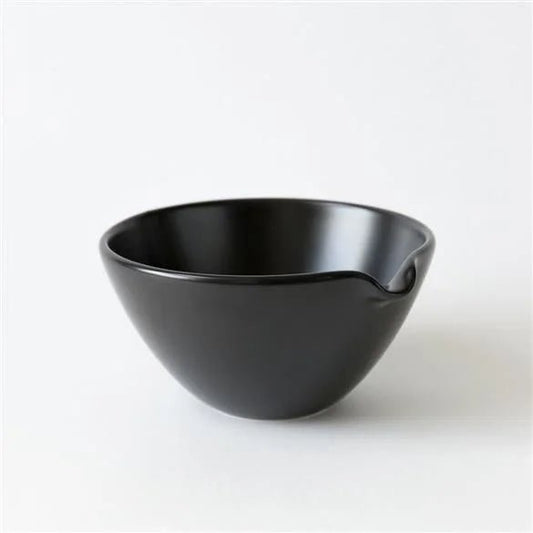 The Rishi Matcha Pouring Bowl is a minimalist black ceramic bowl featuring a small pouring spout, shown against a plain white background.