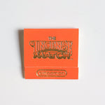An orange matchbook labeled "Matches | The Incense Match" by The Incense Match with "cinnamon" in gold lettering rests on a white surface—perfect as a compact air freshener and thoughtful incense gift.