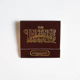 A brown packet labeled "Matches | The Incense Match" by The Incense Match with "coconut" at the bottom sits on a white surface—this innovative air freshener doubles as incense matches, making it an ideal gift for any occasion.