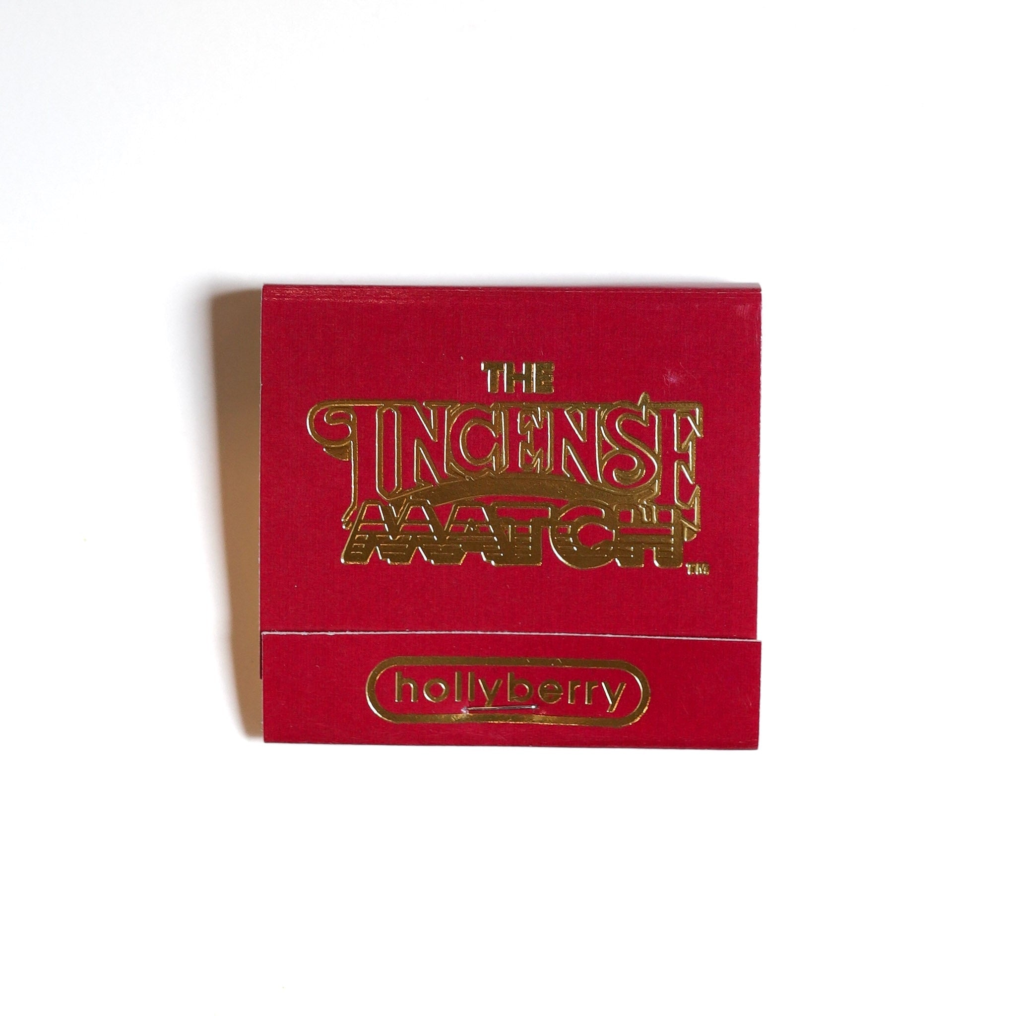 A red "Matches | The Incense Match" by The Incense Match with "hollyberry" on the flap, this compact incense match doubles as an air freshener, shown on a white background.