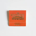 An orange "Matches | The Incense Match" booklet from The Incense Match brand, labeled "musk," sits on a white background—ideal as an incense gift or air freshener with convenient incense matches.